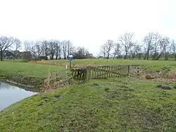 Rechtsachter de onbehuisde met bomen omzoomde wierde waar vroeger de tweede boerderij stond