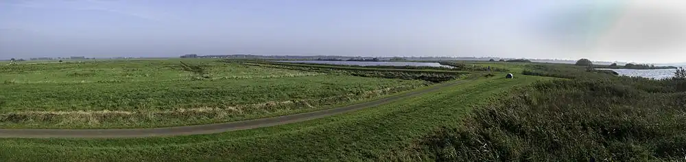 Panorama over het zuidoostelijk deel van de polder vanaf de uitkijktoren. Rechtsachter 'De Tip'. De rietlanden aan de rechterkant fungeren als helofytenfilters: Ze zuiveren het meegevoerde en bezonken slib doordat het riet de voedingsstoffen eruit opneemt.