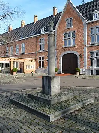 Schandpaal op de Groenplaats, met het poortgebouw op de achtergrond