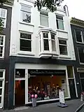 Woonwinkelpand, meermalen verbouwd ouder pand met voorgevel met interieur met stilistische ontlening aan het werk van S. van Ravesteyn