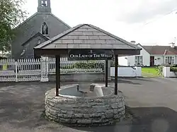 De heilige bron aan de pleinzijde van de kerk met een naamplaat