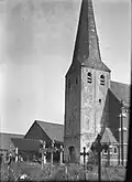 Romaanse kerktoren, beneden van ijzeroersteen, hoger van mergel en met een buitengeleding met lisenen en rondboogfries, na zware oorlogsschade in 1944 gerestaureerd