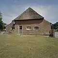 Boerderij van het Kempische langgeveltype, onder rieten wolfdak met voet van pannen; ramen met kleine roedenverdeling en luiken