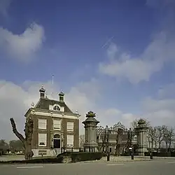 Overzicht hoofdgebouw met toegangshek