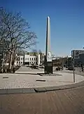 De gedenknaald met op de achtergrond het paleis