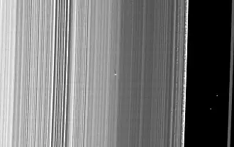 De heldere stip met lange schaduw in het midden is S/2009 S1. De zwarte scheiding aan de rechterkant is de Cassinischeiding van het ringensysteem van Saturnus