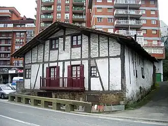 Een historische boerderij met daarachter woontorens in Loiola