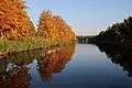 Bomen in herfstkleuren, gespiegeld in het water van het kanaal