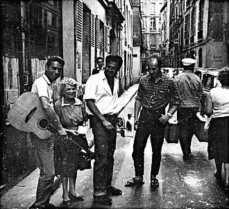 alt=Robin Page en Peter Golding als straatmuzikanten naast de eigenaresse van The Beat Hotel, eind jaren '50