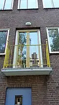 Gekleurd balkon; wit en grijs balkon met gele balustrade en goudkleurige ballen (mei 2019)
