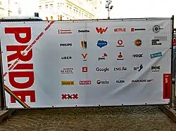 Logo's van de sponsors van Pride Amsterdam, te zien op het hek van het hoofdpodium op de Dam (2018).