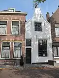 Huis met gepleisterde tuitgevel met schuiframen in stijl