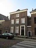 Pand achter lijstgevel voorzien van gecanneleerde pilasters met hoofdgestel