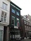 Hoekpand Molenstraat. Huis, waarvan nog de zijgevel met uitgekraagde schoorsteen zichtbaar is. De voorgevel heeft een kroonlijst met triglyphen en metopen