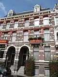 Herenhuis in neorenaissance trant met souterrain. Lijstgevel versierd met banden, blokken en een getoogde ingangsomlijsting. Balcon op voluutconsoles