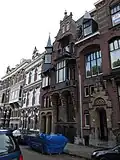 Pand in neorenaissance trant met souterrain. Balcon op consoles, waarboven een houten erker. Afgeknotte trapgevel. Links een driezijdig torentje