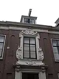 Statig patriciershuis met uit- en inspringende gevelpartijen, rechte kroonlijst; middenpartij met houten gebeeldhouwde versieringen, inwendig rechts en links van de middengang binnenplaatsen met houten betimmeringen met secreten. Fraaie stucwerken in de gang en deuren