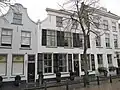 Pand met aan de straat een gepleisterde gevel met ingezwenkte zijkanten, hoekvoluten en een houten kroonlijst
