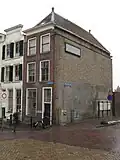 Pand voorzien van voorgevel met inspringend bovengedeelte, geflankeerd door gebeeldhouwde voluten en bekroond door een houten kroonlijst
