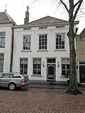 Pand met schilddak en gepleisterde lijstgevel. Vensters met zes- en twaalfruitsschuiframen; liggende vensters in het hoofdgestel. Hardstenen stoeppalen met smeedijzeren hekken