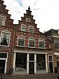 Pand met trapgevel van het Zuid-Hollandse type met geprofileerde waterlijsten, geblokte vensternissen met afgeschuinde dagkanten en vlechtwerk in de boogtrommels, alsmede versierde toppilasters op ma