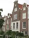 Huis met gevel onder ingezwenkte hals met rollagen en fronton