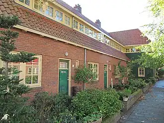 Gevarieerd samengestelde reeks van vier woningen op L-vormige grondslag met poort aan rechterzijde