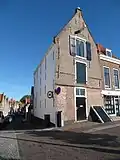 Pakhuis met tuitgevel, overkragend boven pui