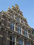 Pand met monumentale gevel in renaissancetrant met grote trappen, versierd met vleugelstukken en obelisken en een bekronend fronton, waaronder het jaartal 1631