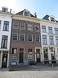 Oorspronkelijk een huis, thans in twee woningen gesplitst onder hoog schilddak, waarin dakkapel met fronton, gevel met kroonlijst (ca. 1800)