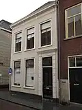 Huis met witgeverfde lijstgevel, ingang met geblokte witte pilasters