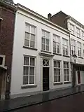 Huis met witgepleisterde lijstgevel en ingangspartij met geblokte pilasters en kroonlijstje met triglyphen