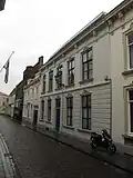 Huis met gepleisterde lijstgevel, beganegronds gebosseerd