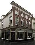 Huis met eenvoudige lijstgevel in schoon werk, kroonlijst op klossen en hoog schilddak, op de hoek van de molstraat