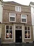 Huis met lijstgevel in schoon werk, ingang met kroonlijst op geblokte pilasters en jaarankers 1590