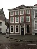 Huis op de hoek van de kerkstraat, met geelgeverfde lijstgevel, schilddak, kroonlijst op consoles, lage zolderverdieping