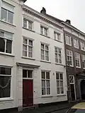 Huis met gepleisterde empire gevel, kroonlijst op klossen, ingang met geblokte pilasters