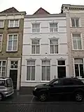 Huis met gepleisterde en van stuckuiven boven de vensters voorziene lijstgevel, plat dak