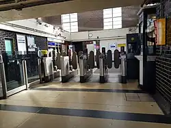 De stationshal met OV-poortjes gezien uit de gang tussen hal en trappen.