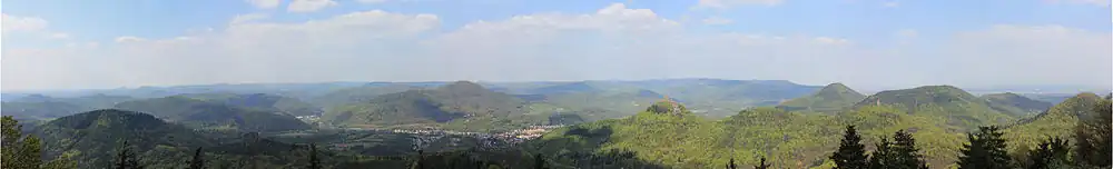 Het Paltserwoud is een zwaar ingesneden laaggebergte met veel heuvelvormen en dichte bebossing: panoramisch uitzicht vanaf de Rehberg(toren) op de Trifels in noordelijke richting