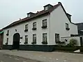 Voormalige Limburgse hoeve, ten dele in vakwerk, ten dele in gepleisterd, geverfd en schoon metselwerk opgetrokken, deels tot pension verbouwde rond binnenplaats, ten dele met verdieping en onder met rode en blauwe Hollandse en rode muldenpannen gedekte zadeldaken