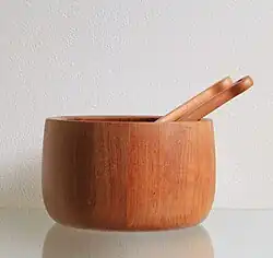 Foto van een teakhouten saladeschaal met slacouvert. De foto van de schaal is genomen tegen een witte achtergrond.