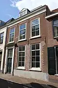 Huis bestaande uit twee bouwlagen met kap loodrecht op de straat en een kelder met kruisgewelven