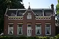 Boerderij, bestaande uit een woonhuis met aangebouwd bedrijfsgedeelte, gebouwd op een kunstmatige verhoging. In de gevel van het huis zijn elementen van Neo-Renaissance verwerk