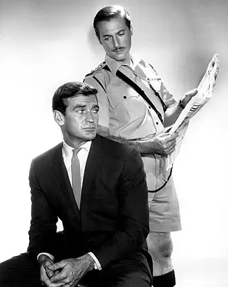 Taylor (zittend) als Glenn Evans met Lloyd Bochner als Inspector Neil Campbell in de tv-serie Hong Kong, 1961.