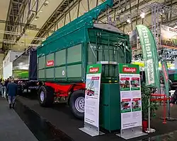 Driezijdige kipper met dubbele as (draaikrans bovenop voorste as). Let op de informatieborden ervoor; het linker toont een zijdelingse wagondeur, het rechter toont links bovenaan een ééndelige klepdeur met drie graanschuiven, rechts bovenaan een tandem driezijdige kipper, links onderaan het driezijdige kippen aan de rechterzijde, en rechts onderaan een hydraulische zijdeur.