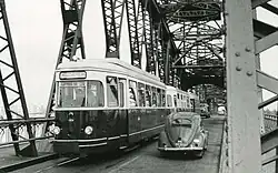Tram op de Spijkenisserbrug; zo smal was de brug: er kon net een kleine auto de tram passeren, maar vrachtauto's moesten wachten. Dieselelektrisch tramstel RTM MBD 1700 EB 1701-1702 'Sperwer'; 1964. In de tegenrichting reden de (stoom)trams tegen de rijrichting in; daarom waren er rode lichten.