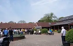 Sammy Miller demonstreert een AJS Porcupine racer op de binnenplaats van zijn museum