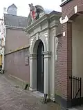 Fraaie natuurstenen poortomlijsting, voortijds aan Kleine Poot als onderdeel van het huis Het Lam. Naar voorbeeld van de zuiderlijke poort van de Westerkerk te Amsterdam[4]
