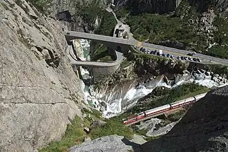 Zicht op de Schöllenenschlucht vanuit het Restaurant Teufelsbrücke met op de voorgrond de Teufelsbrücke uit 1917, de spoorbrug van de Schöllenenbahn Göschenen - Andermatt, de kloof waar de Reuss doorstroomt en de tweede en derde wegbrug.